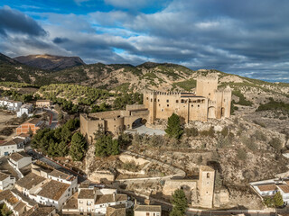 Wall Mural - Aerial view of  Velez Blanco castle on a hilltop and town with one or two floor houses whitewashed walls and tiled roofs with dramatic cloudy sky in Andalusia Spain