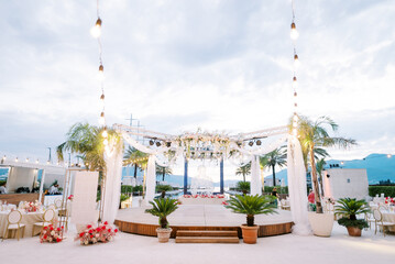 Wall Mural - Round stage decorated with garlands stands between the laid tables