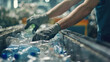 Leinwandbild Motiv The hands of the employee in gloves are close-up. On the conveyor for recycling and sorting garbage from plastic bottles, glasses of different sizes, garbage sorting and recycling concept