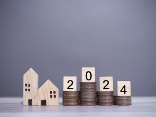 Poster - Wooden blocks with number 2024 on stack of coins and miniature house. The concept of Property investment, House mortgage, Real estate.