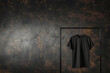 Mock-up t-shirt noir en coton à manches courtes sur un cintre suspendu à un portant noir sur un fond texturé marron et noir avec espace négatif pour texte copyspace