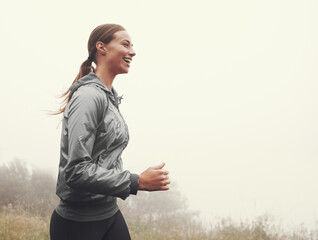 Canvas Print - Nature, energy and woman running in fog on mountain road for race, marathon or competition training. Sports, exercise and athlete with cardio workout for fitness in misty outdoor woods or forest.