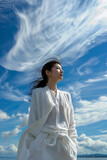 Fototapeta Konie - a young asian woman in white outfit and cardigan standing under blue sky