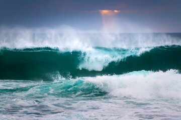 Wall Mural - Big ocean waves on the beach at sunset. Atlantic ocean in Nazare, Portugal.