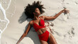 Top down view of a black African American beautiful young woman sunbathing in swimwear on a white sand beach on sunny summer day