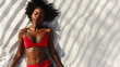 Top down view of a black African American beautiful young woman sunbathing in swimwear on a white sand beach on sunny summer day with copy space background