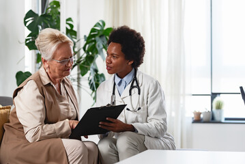 Wall Mural - Doctor specialist consulting a patient at the clinic. A female doctor is talking with a female elderly patient.