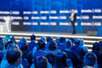 Wall Mural - Audience attentively listening to keynote speaker at a corporate event. Blurred conference background.