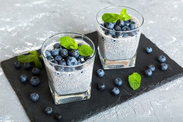 Wall Mural - Healthy breakfast or morning with chia seeds vanilla pudding and blueberry berries on table background, vegetarian food, diet and health concept. Chia pudding with coconut milk and blueberry