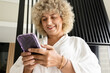 Woman in a White Bathrobe Delightfully Engages With Her Smartphone. The Image Evokes Feelings of Leisure, Connectivity, And The Joy of Digital Communication.