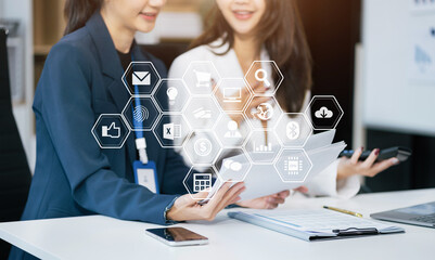 Business documents on office table with smart phone, tablet and laptop computer and graph with social network diagram and two colleagues discussing data in office.