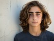 © imagineRbc - A multiracial young man with long hair standing against a wall in an urban setting