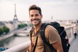 Portrait of a smiling young man with backpack standing in Paris, France