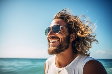 Wall Mural - Portrait of a happy young man with long curly hair and sunglasses at the beach