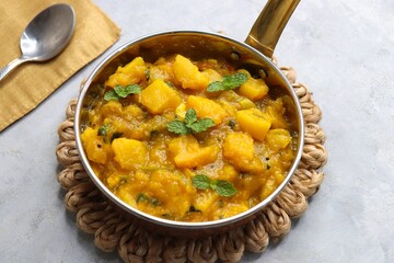 Wall Mural - Pumpkin curry is a rich and aromatic dish made with tender pumpkin chunks cooked in a blend of spices like cumin, coriander, and turmeric along with onions and tomatoes. Kaddu masala. copy space