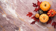 A group of pumpkins with dried autumn leaves and twig, on a light maroon color marble