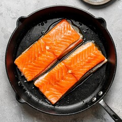 Overhead view of two raw salmon fillets in a pan waiting to be pan seared or fried for a delicious seafood meal