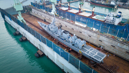 war ship maintenance in dry dock shop. War Ship floating on dry dock. Military navy ship get maintenance and service.