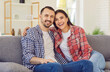 © Studio Romantic - Harmonic relationships and sincere feelings. Portrait of Caucasian young couple in love sitting on sofa smiling and hugging. Happy beautiful couple in checkered shirts smiling broadly at camera.