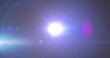 Image of spotlight with lens flare and light beams moving over dark background