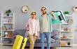 Happy cheerful smiling loving married couple with packed up suitcases ready for summer holiday standing together in living room at home. Traveling, vacation concept 