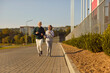 © Studio Romantic - Happy smiling sporty senior couple wearing sportswear jogging in the park having sport workout. Elderly man and woman running outdoors. Workout jog in nature, exercising for retired concept.