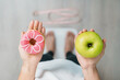 woman on weight scale and hand hold green Apple and donut, choose between fruit is Healthy and sweet is Unhealthy junk food. Dieting control, Weight loss, Obesity, eating lifestyle and nutrition