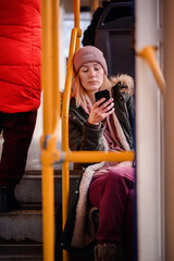 Wall Mural - Smiling Young Woman Texting on Phone During Bus Journey