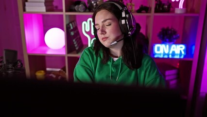 Poster - A young woman wearing a headset immersed in a colorful gaming room at night.