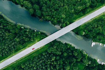 Wall Mural - Aerial view of bridge road with car over blue river and green woods in Finland