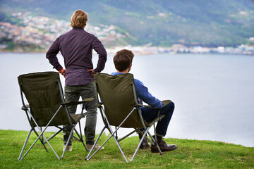 Sticker - Camping, chair and people relax at lake with landscape in countryside, nature or calm vacation. Summer, holiday and back of friends sitting on grass at river with peace in environment together