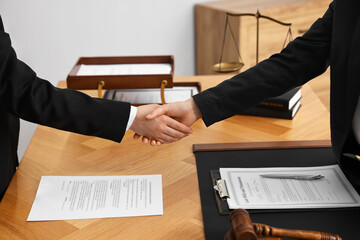 Wall Mural - Notary shaking hands with client at wooden table in office, closeup