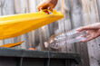 Waste Recycling Concept. Unrecognizable lady throwing plastic bottle into yellow recycle bin container outdoors, sorting garbage, enjoying zero waste living, cropped image with selective focus.