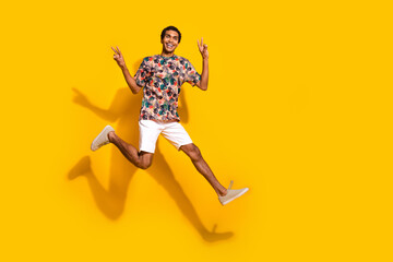 Wall Mural - Full length photo of cool friendly guy dressed print t-shirt jumping high showing v-signs empty space isolated yellow color background