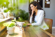 © Dragana Gordic - Smiling Woman Listening to Music at Work by Using her Smartphone and Wireless Earphones. Young beautiful woman using airpods and a laptop for an online conference call with her colleagues at work