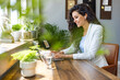 © Dragana Gordic - Smiling pretty skilled young woman with wireless earbuds sitting at table in office and working with modern computer. Happy businesswoman taking a video call in a co-working space