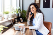 © Dragana Gordic - Cheerful young businesswoman having a video call in a modern co-working space. Happy female entrepreneur communicating with her business associates while working remotely.