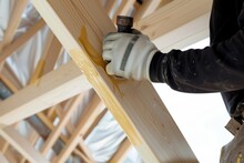 Man Sealing Timber Frame Joints Against Weather