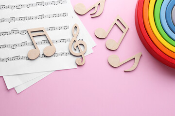 Sticker - Baby songs. Music sheets, wooden notes and toy rainbow on pink background, flat lay