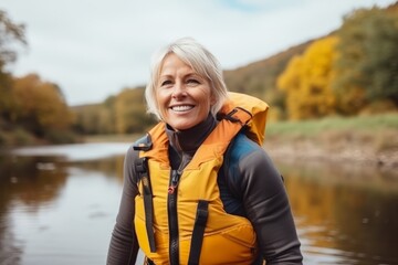 Canvas Print - Portrait of a happy senior woman standing by the lake in autumn