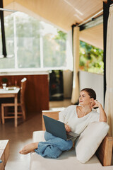 Wall Mural - Happy Woman Working on Laptop in Modern Home Office, Surrounded by Technology and Lifestyle Essentials