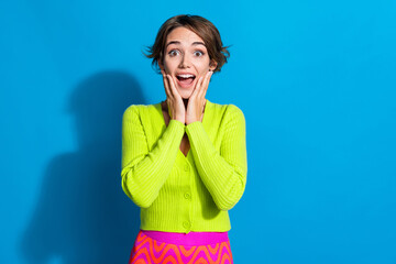 Poster - Portrait of impressed lovely girl arms touch cheekbones open mouth empty space isolated on blue color background