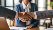 A bank manager is shaking hands with a satisfied customer inside a modern bank interior - celebrating a completed deal - wide format