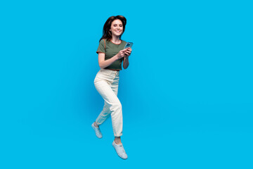 Canvas Print - Full size photo of smart lovely woman wear green t-shirt run to empty space with smartphone in hands isolated on blue color background