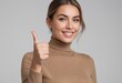 © kotlyarn - A cheerful woman in a turtleneck sweater gives a thumbs up, her bright smile suggesting confidence and satisfaction.