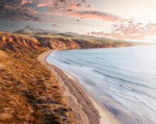 Aerial View Of Sellicks Beach Cliffs During Golden Hour With Pink Clouds In The Background And A Rocky Shore With Vegetation In The Foreground, Sellicks Beach, South Australia, Australia.