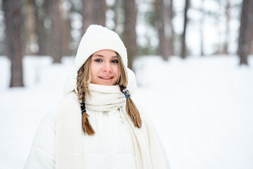 Wall Mural - Beautiful Caucasian girl with pigtails in a white coat in winter in the forest, portrait of a young girl