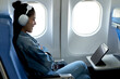 young woman sitting on a plane looking at a tablet for information and entertainment while traveling on an airline  making business and news non-stop even though she is far away while traveling
