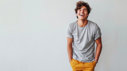 Sticker - A joyous man in a gray t-shirt and yellow pants is standing against a white wall, laughing with his eyes closed in an expression of pure happiness.