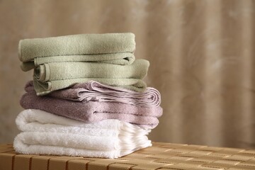 Wall Mural - Stack of soft towels on wicker bench indoors, closeup. Space for text